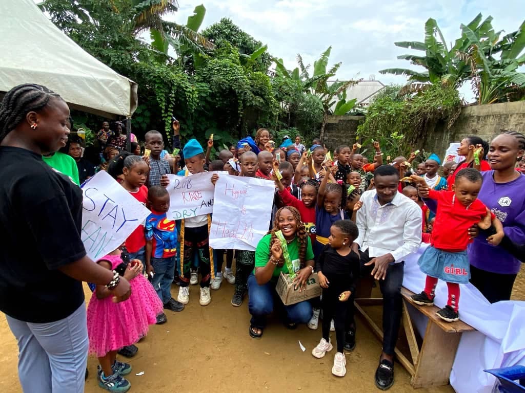 Children holding handmade signs reading 'Rub, rinse and dry' and 'Hygiene is health' at an Eco Alliance hygiene outreach session